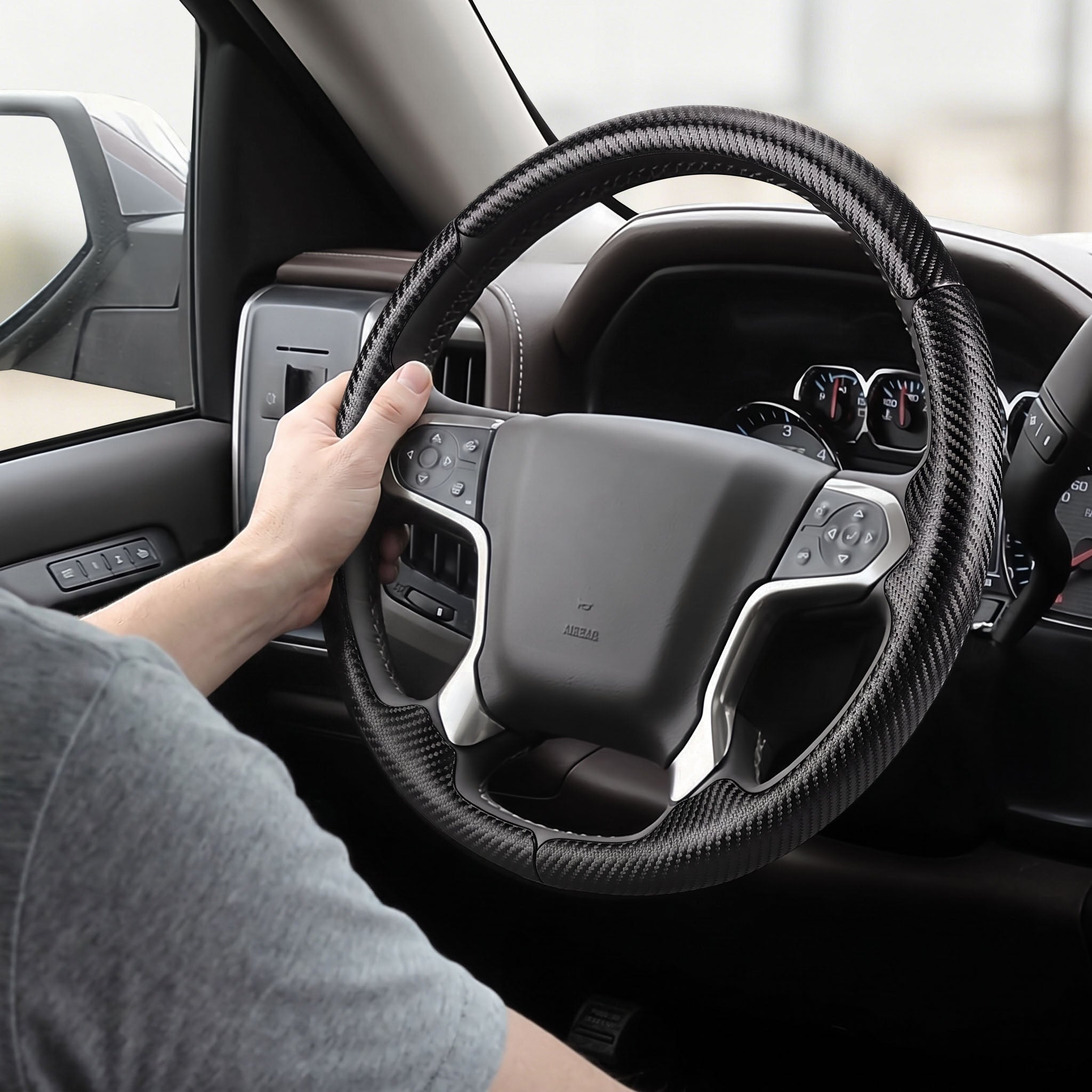 Installed view of matte black carbon-fiber-style 3-piece steering wheel cover for Chevy Silverado 1500 2014-2018 & Silverado 2500/2500HD/3500/3500HD 2015-2019 with driver holding the wheel#color=matte black