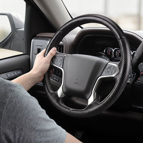 Installed view of matte black carbon-fiber-style 3-piece steering wheel cover for Chevy Silverado 1500 2014-2018 & Silverado 2500/2500HD/3500/3500HD 2015-2019 with driver holding the wheel#color=matte black