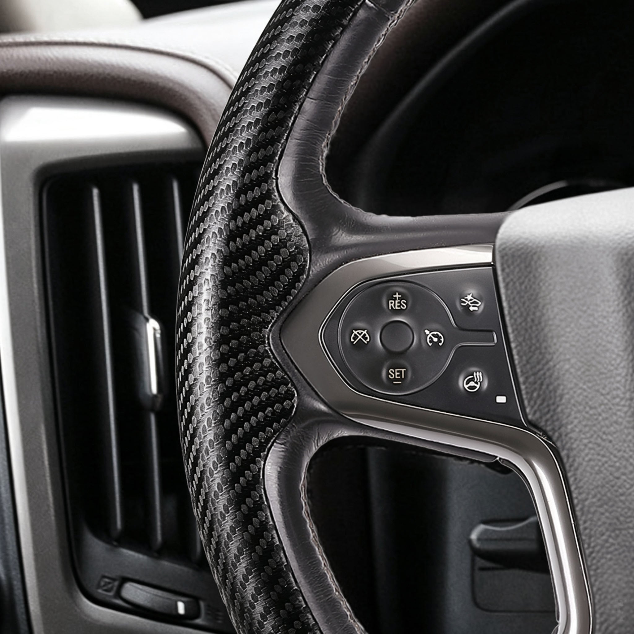 Close-up of a matte black carbon-fiber-style 3-piece steering wheel cover for Chevy Silverado 1500 2014-2018, showing its ergonomic 3D contours and precise custom fit