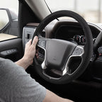 Installed view of black perforated leather 3-piece steering wheel cover for Chevy Silverado 1500 2014-2018 & Silverado 2500/2500HD/3500/3500HD 2015-2019 with driver holding the wheel#color=black perforated leather