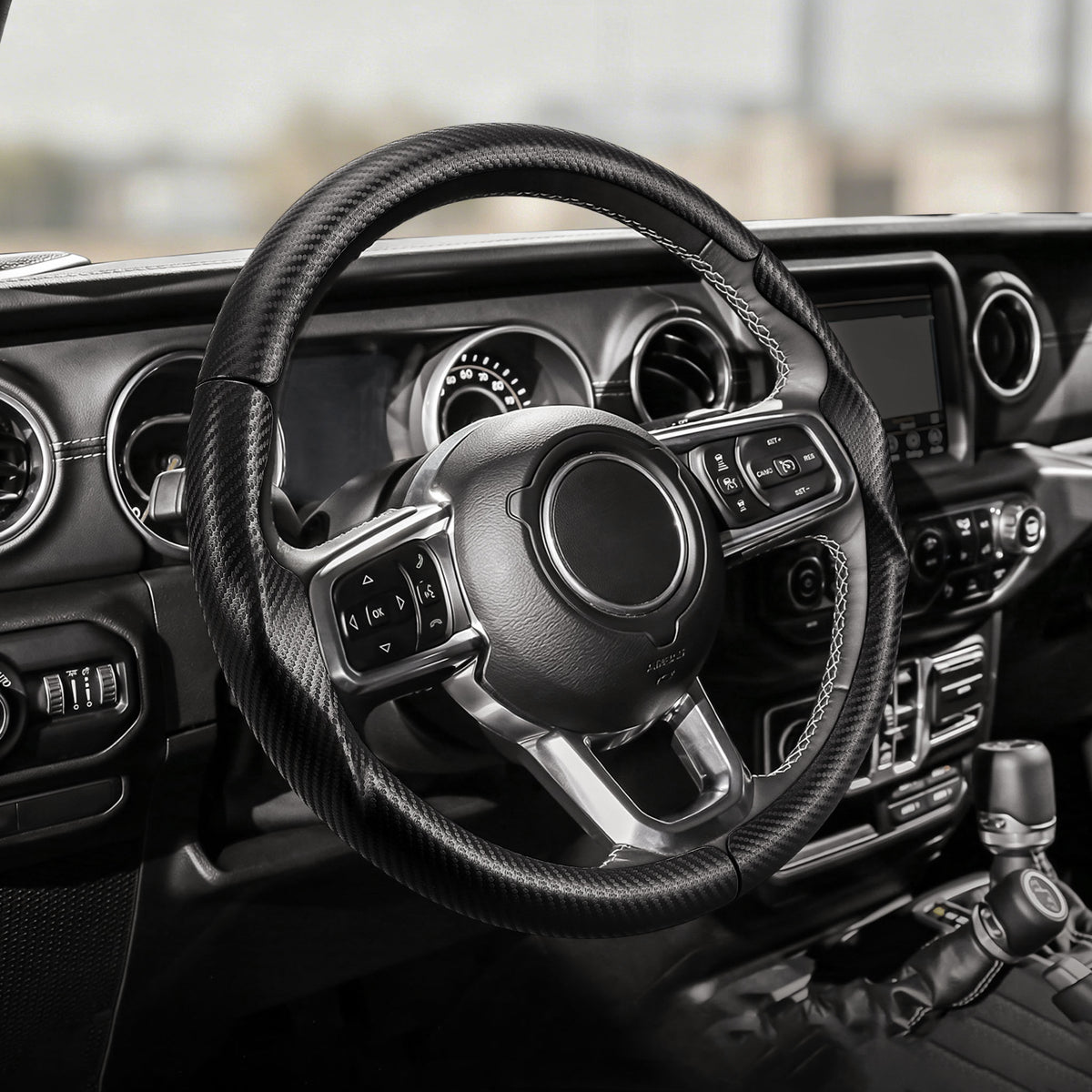 Cockpit view of matte black carbon-fiber-style 3-piece steering wheel cover for Jeep Wrangler 2018-2026