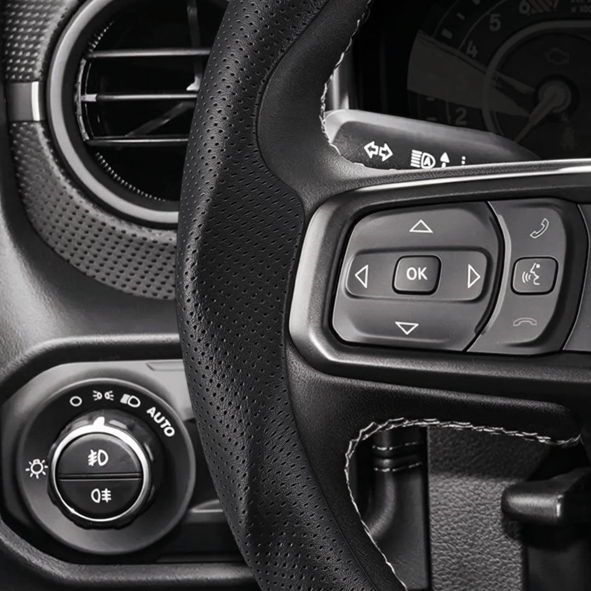 Close-up of a black perforated leather 3-piece steering wheel cover for Jeep Wrangler 2018-2026, showing its precise custom fit