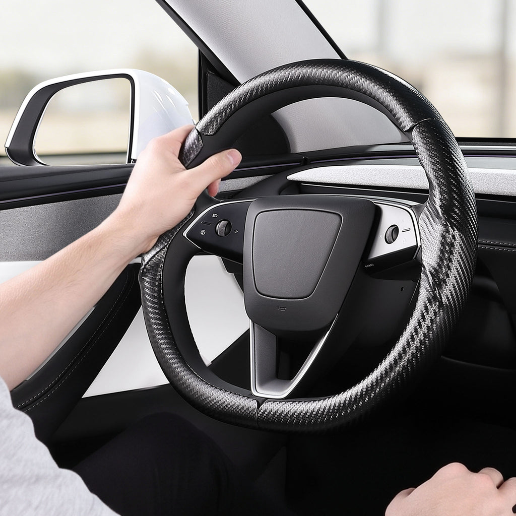 Installed view of matte black carbon-fiber-style 3-piece steering wheel cover for Tesla Model 3 2024-present with driver holding the wheel#Model=Model 3 2024-present|color=matte black