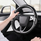 Installed view of matte black carbon-fiber-style 3-piece steering wheel cover for Tesla Model 3 2024-present with driver holding the wheel#Model=Model 3 2024-present|color=matte black