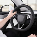 Installed view of black perforated leather 3-piece steering wheel cover for Tesla Model 3 2024-present with driver holding the wheel#Model=Model 3 2024-present|color=black perforated leather