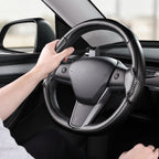 Installed view of matte black carbon-fiber-style 3-piece steering wheel cover for Tesla Model Y 2020-2024 with driver holding the wheel#Model=Model Y 2020-2024|color=matte black