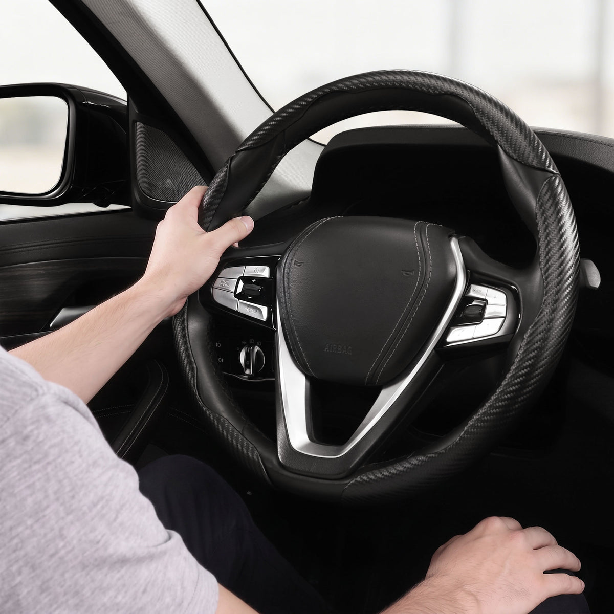 Installed view of matte black carbon-fiber-style 3-piece steering wheel cover for 14.5-15 Inch Wheels with driver holding the wheel#color=matte black