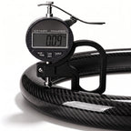 Digital thickness gauge showing the 0.09-inch ultra-slim profile of a glossy black carbon-fiber-style steering wheel cover#color=glossy black